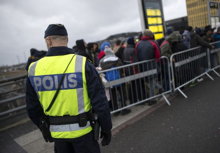 A police officer keeps guard as migrants arrive at Hyllie station outside Malmo