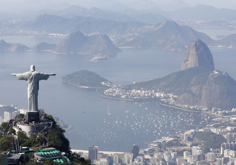Tourists visit the Christ the Redeemer statue with Sugarloaf Mountain (R) in Rio de Janeiro