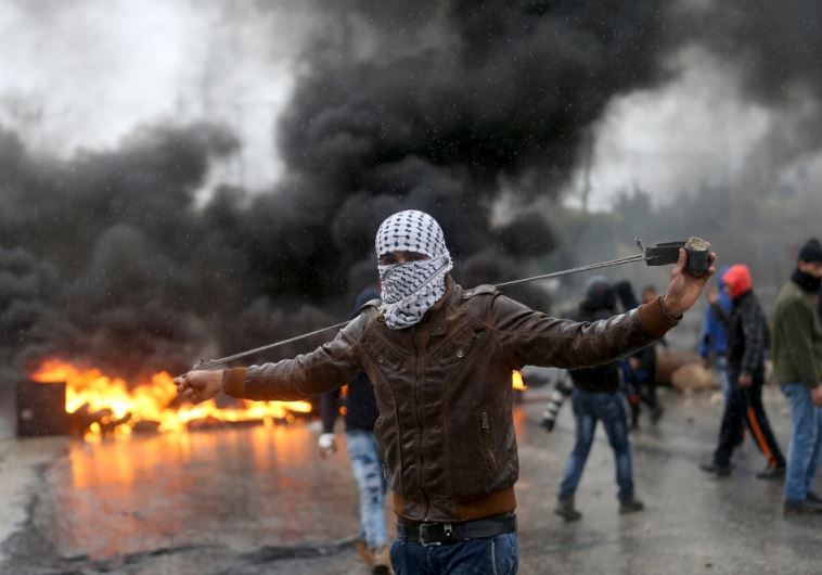 A Palestinian protester prepares his sling to hurl stones towards Israeli troops 