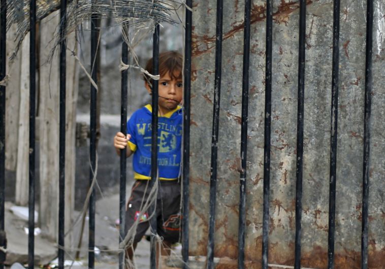A Palestinian boy looks through the gate of his family's house at Shatti (beach) refugee camp in Gaz