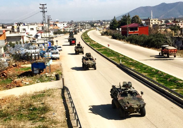 Turkish military vehicles drives through a town near the Syrian border