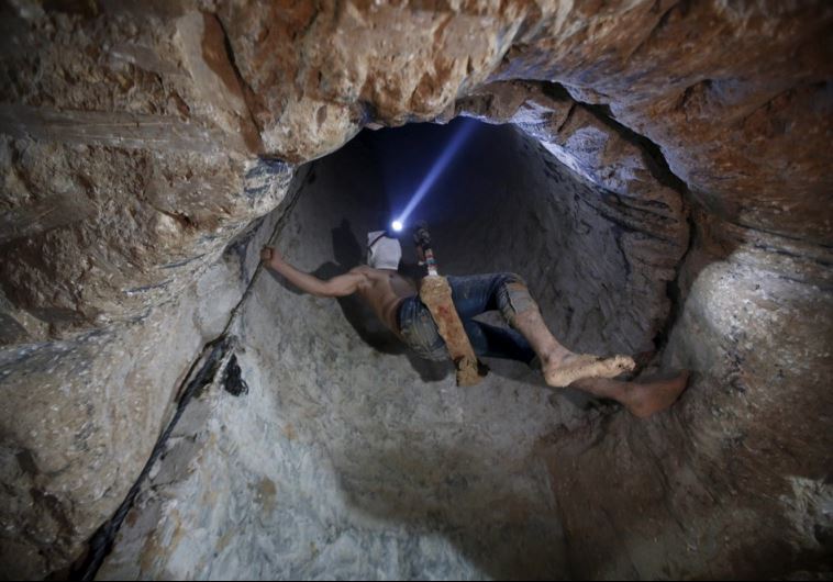 A Palestinian worker is lowered on a rope into a smuggling tunnel that was flooded by Egypt