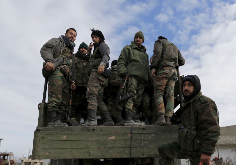 Forces loyal to Syria's President Bashar al-Assad stand on a military truck in the town of Rabiya