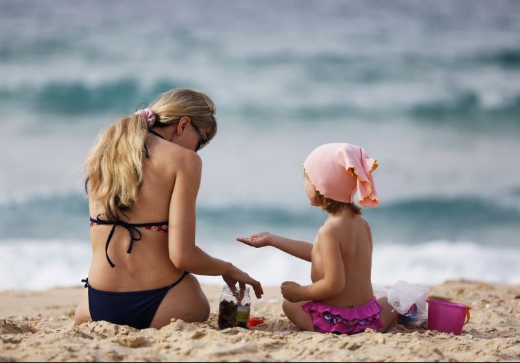 A woman and a girl sit in front of the Mediterranean at the beach in Ashkelon