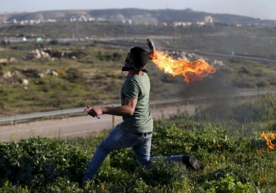 A Palestinian protester hurls a Molotov cocktail towards Israeli troops during clashes