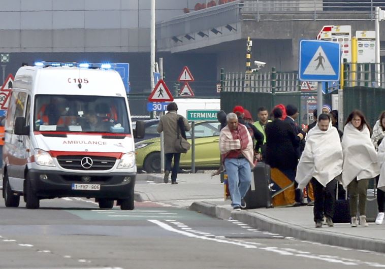  People wrapped in blankets leave the scene of explosions at Zaventem airport near Brussels, Belgium