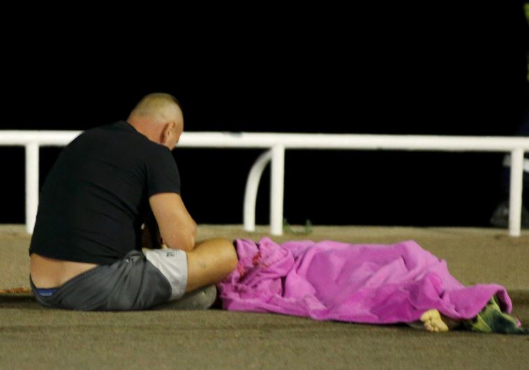 A man sits next to a body seen on the ground July 15, 2016