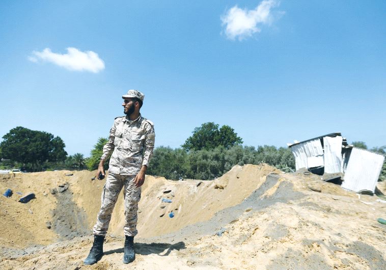 A HAMAS security official inspects a crater yesterday left by an Israeli air strike in retaliation f