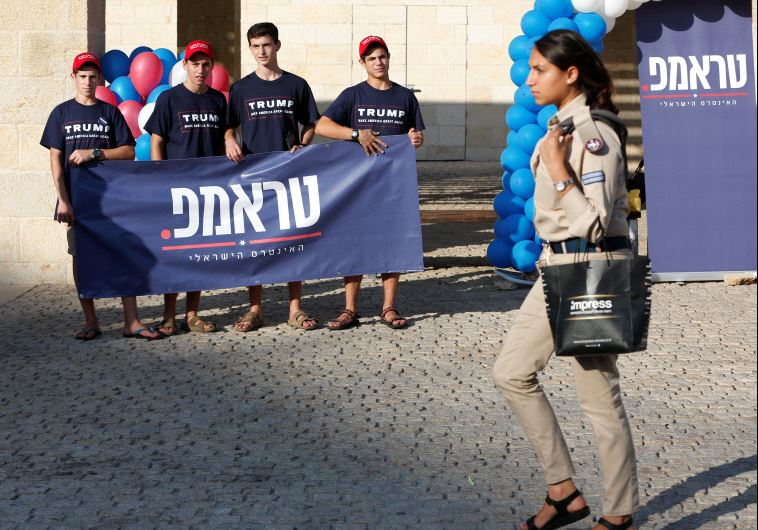 An Israeli soldier walks past members of the US Republican party's election campaign team in Israel,