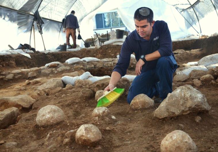  IAA Excavation Co-Director Kfir Arbib cleans one of the unearthed sling stones found at the site