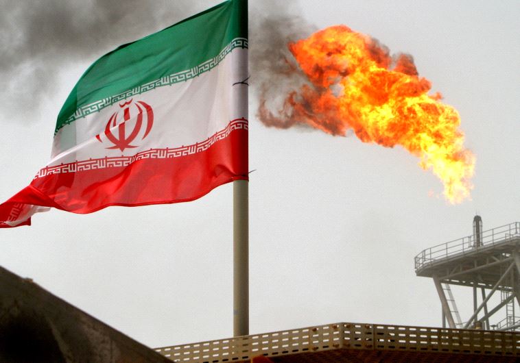 A gas flare on an oil production platform in the Soroush oil fields is seen alongside an Iranian fla