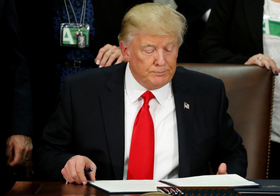 U.S. President Donald Trump reads an executive order before signing it at Homeland Security headquar