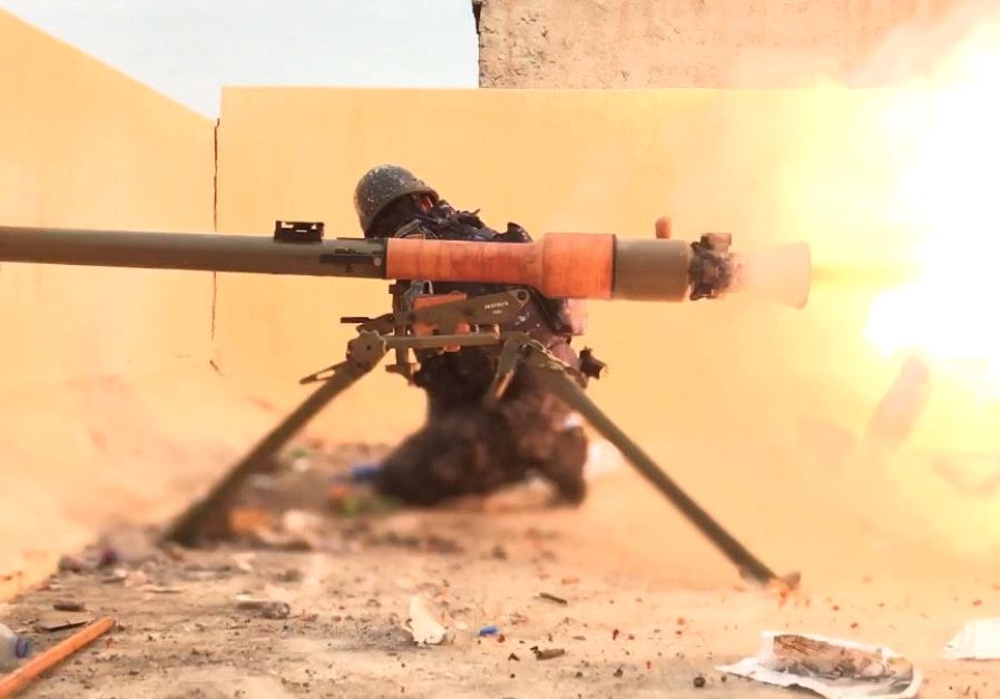 A FIGHTER with Iraqi forces looks away as his weapon fires ISIS targets in 