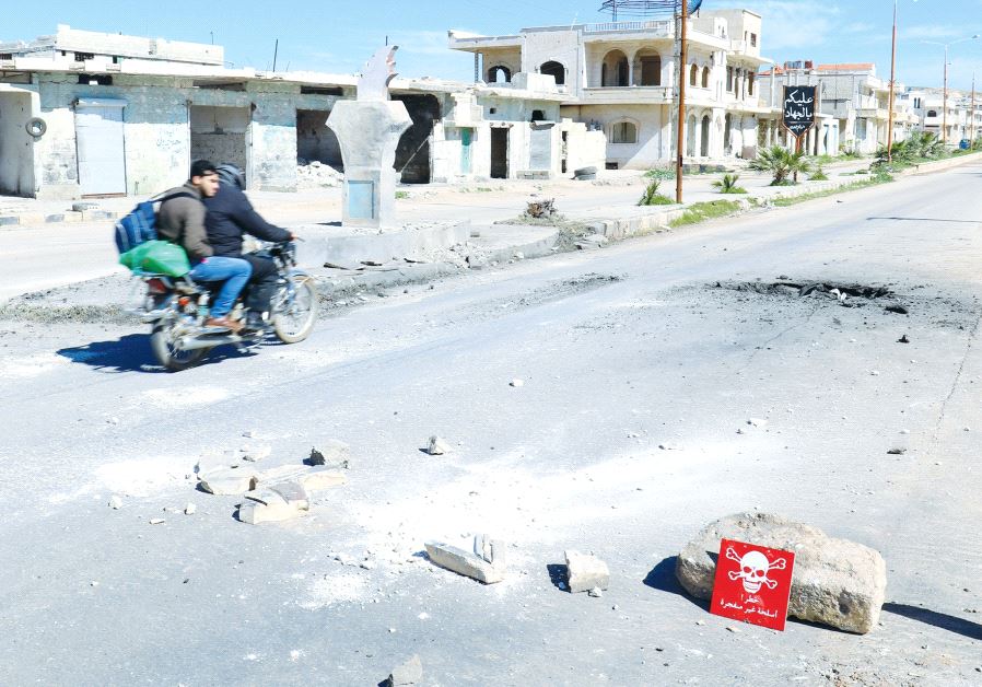 MEN RIDE a motorcycle yesterday past a hazard sign in rebel-held Khan Sheikhoun in Syria’s Idlib pro