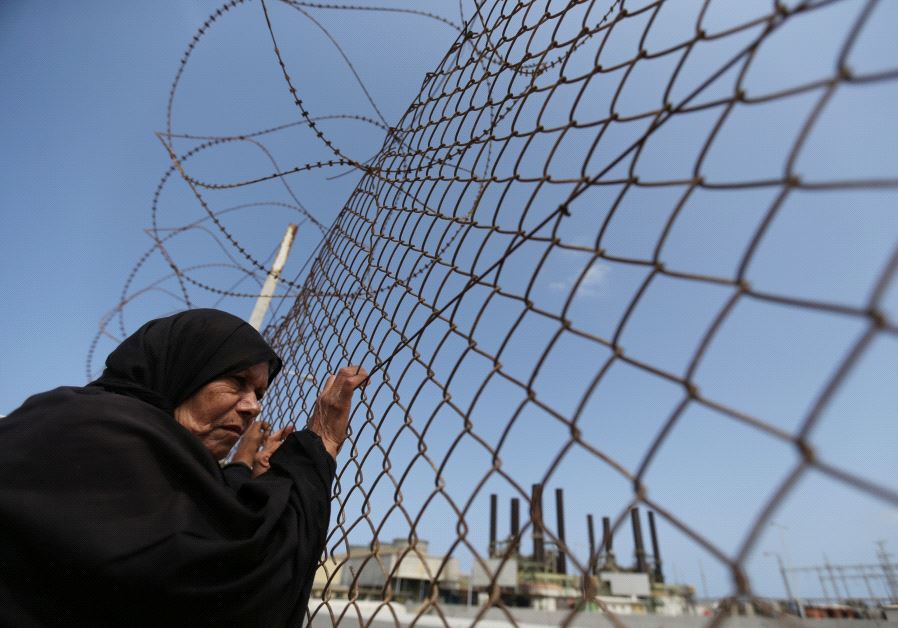 A Palestinian woman stands by a fence during a protest calling for an end to the power crisis, outsi