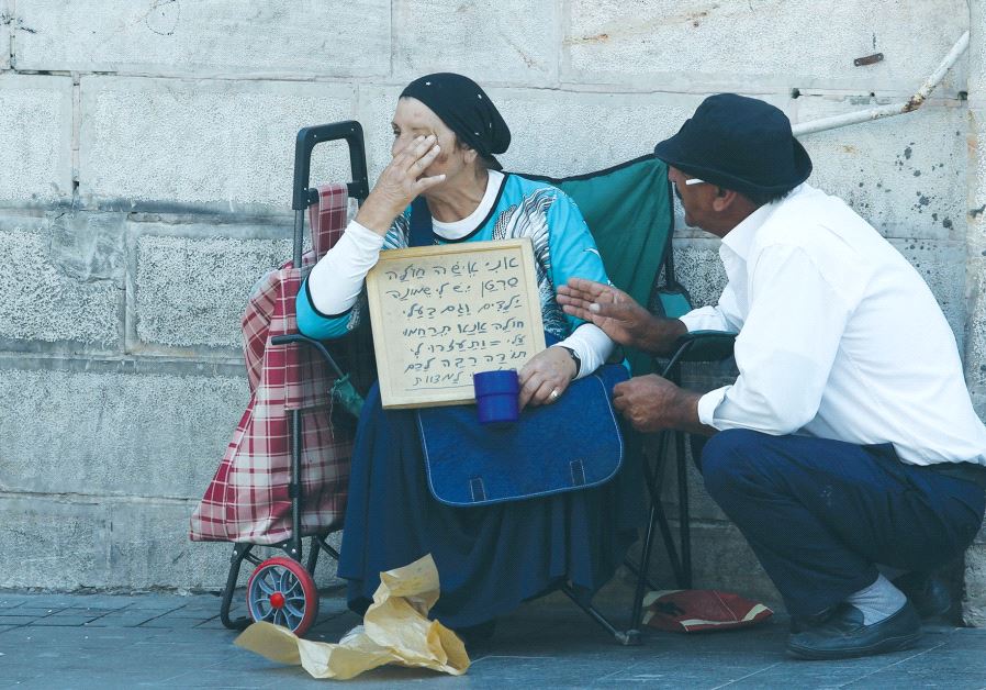 A PASSERBY stops to console a poor woman in Jerusalem in 2015.