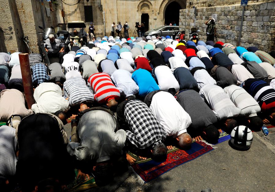 Palestinian men pray outside the Temple Mount after Israel removed the new security measures there, 