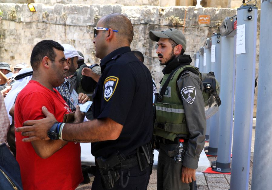An Israeli police officer checks the identity of a Palestinian man next to newly installed metal detectors at an entrance to the compound known to Muslims as Noble Sanctuary and to Jews as Temple Mount, in Jerusalem's Old City July 16, 2017. (Reuters)
