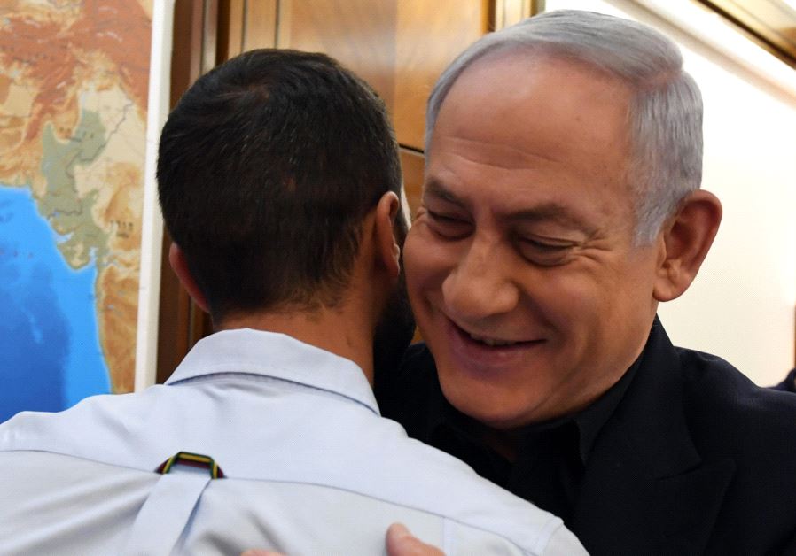 Israeli Prime Minister Benjamin Netanyahu hugs the security guard from the Israeli embassy in Amman Jordan who was stabbed by a terrorist (CHAIM TZACH/GPO)
