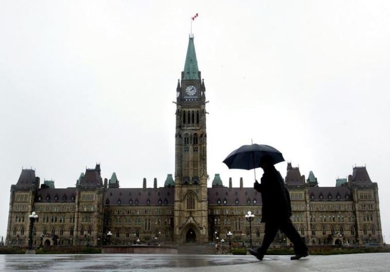 A pedestrian walks in the rain on Parliament Hill in Ottawa, Canada.
