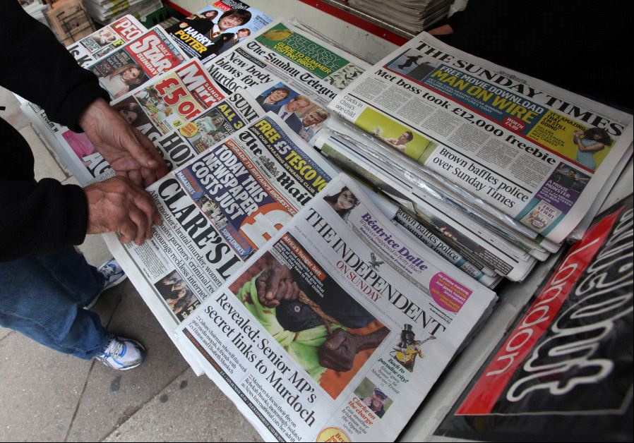 A man buys a Sunday newspaper at a news stand in London July 17, 2011.