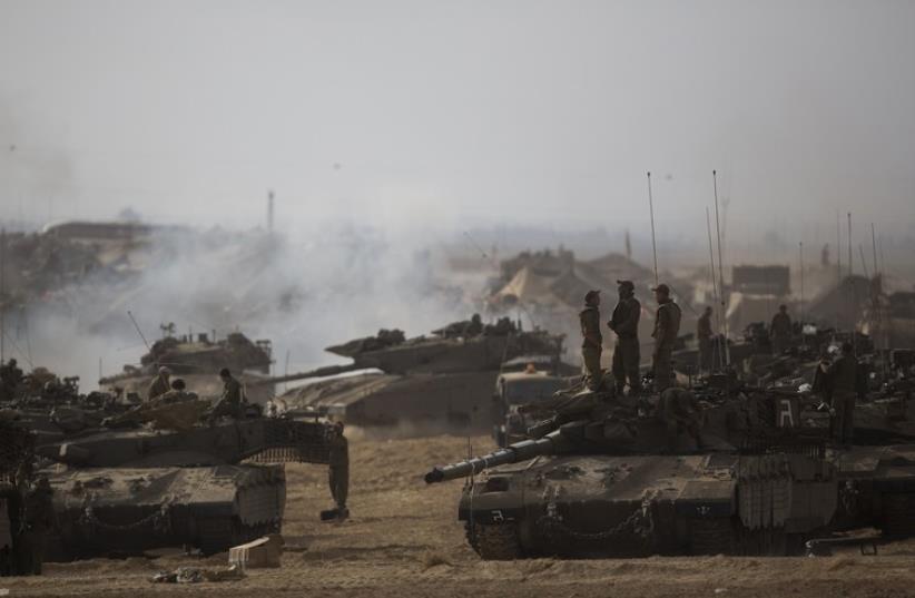 Israeli soldiers stand atop a tank at a staging area, near the border with the Gaza Strip (photo credit: REUTERS)