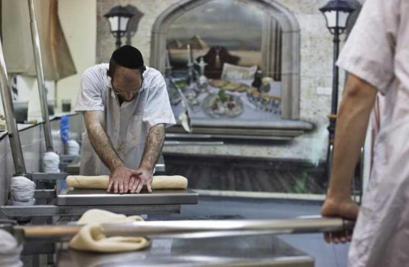 An ultra-Orthodox Jewish man kneads dough as he prepares matza (photo credit: REUTERS)