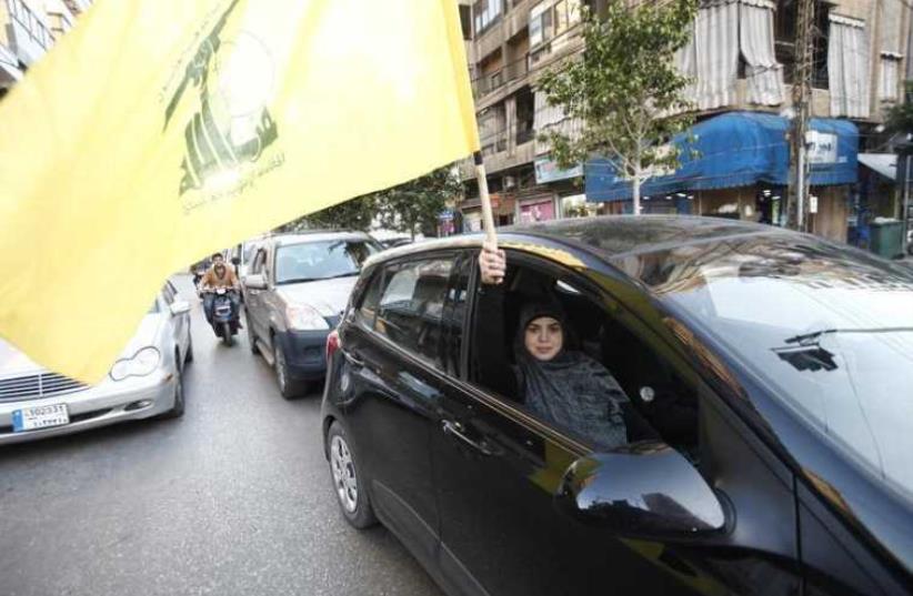 A Hezbollah supporter waves a flag in Beirut's southern suburbs (photo credit: REUTERS)