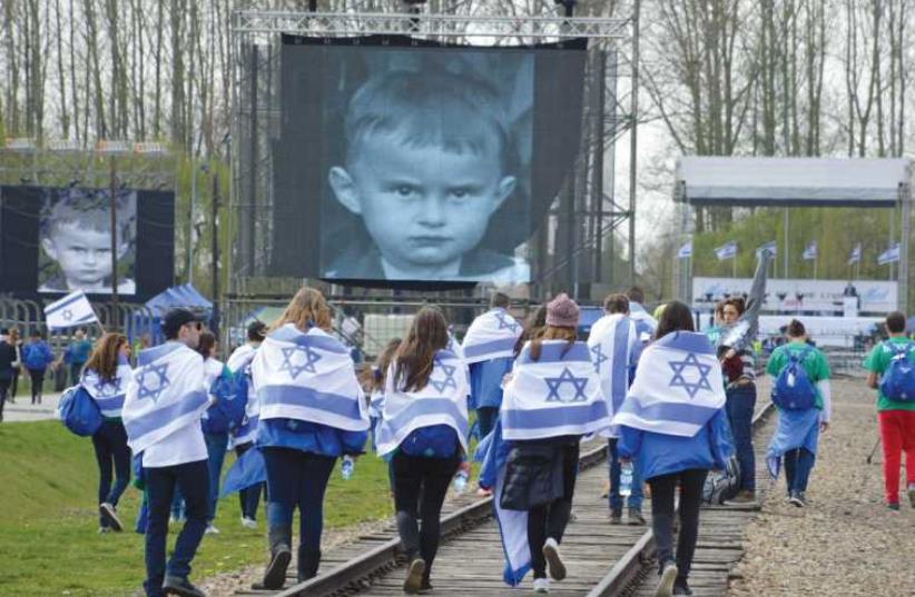 Young people take part in the 2015 March of the Living, with Israeli flags draped over their shoulders (photo credit: Courtesy)