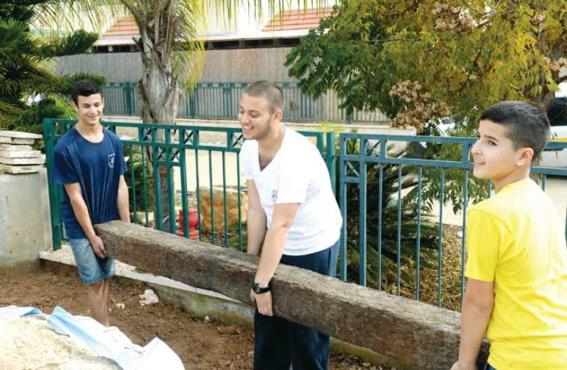 (From left to right) Sagi Farhi, Lidor Fachima and Iddo Ben-David help the Bayhesain family fix up their garden. (photo credit: KOBY KOENKAS)