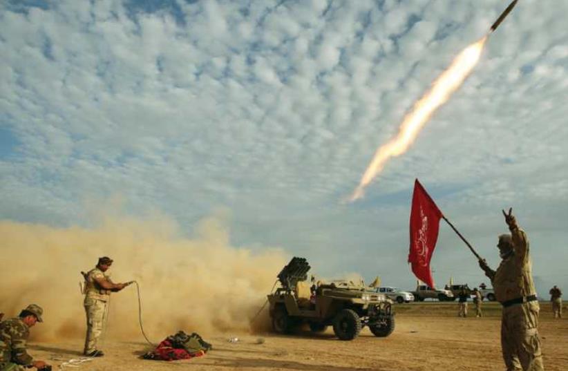 SHI’ITE FIGHTERS launch a rocket last month during clashes with Islamic State on the outskirts of al-Alam, Iraq. (photo credit: REUTERS)