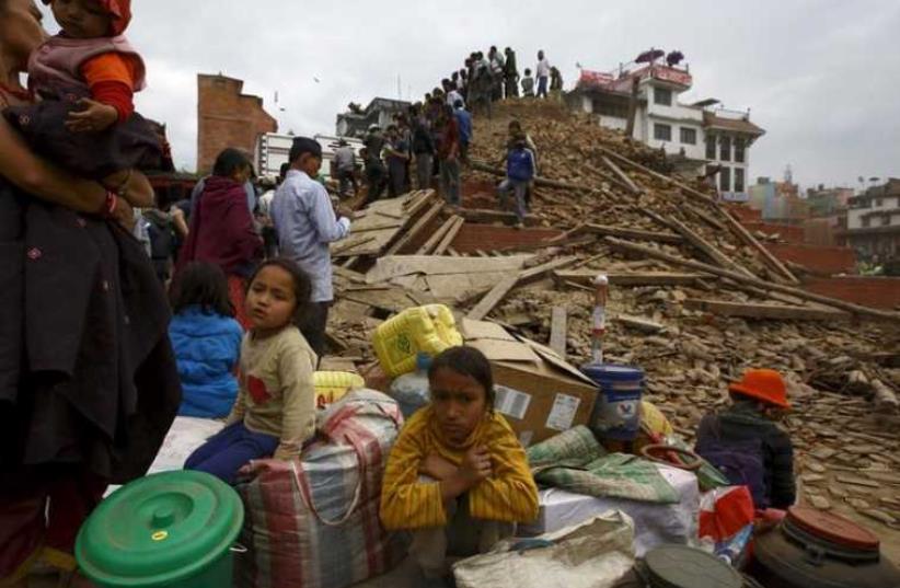 People sit with their belongings outside a damaged temple in Bashantapur Durbar Square after a major earthquake hit Kathmandu, Nepal April 25, 2015. (photo credit: REUTERS)