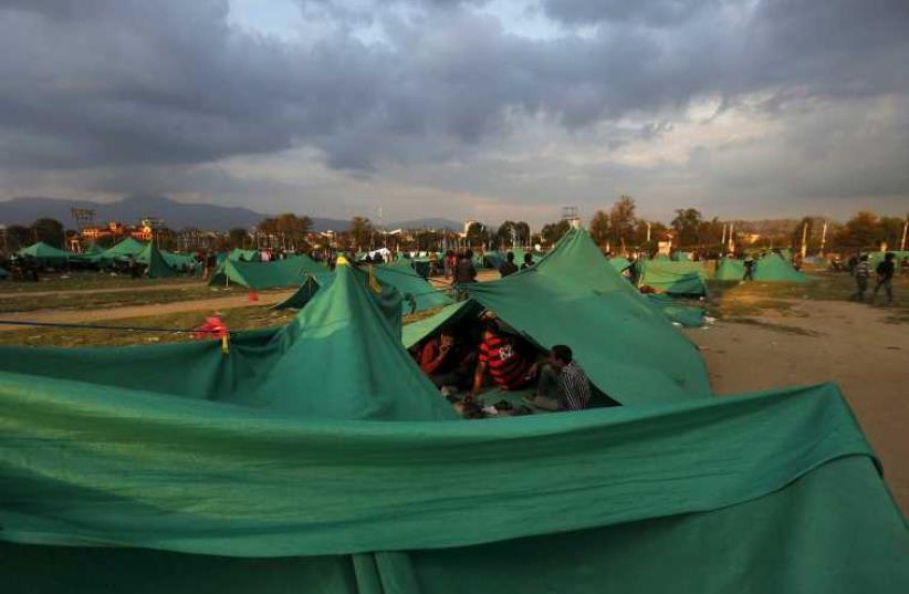 People sit inside their makeshift shelter on open ground after an earthquake in Kathmandu, Nepal April 26 (photo credit: REUTERS)