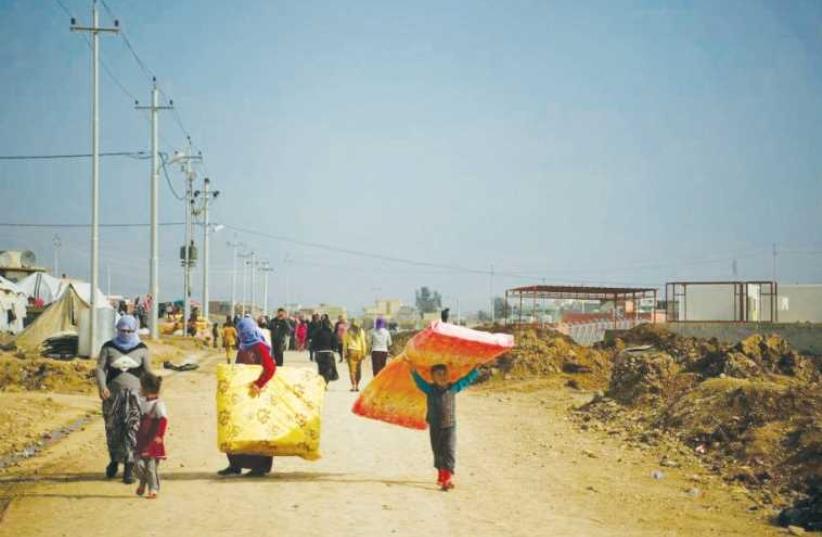 Refugees in Dohuk, Iraqi Kurdistan, carry mattresses provided by IsraAid. (photo credit: ISRAAID)