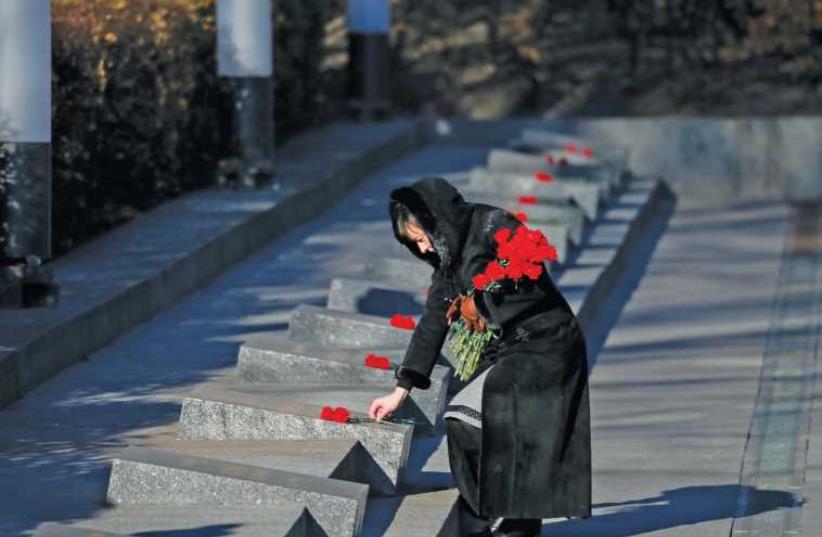 A WOMAN lays flowers during a wreath laying ceremony at the Unknown Soldier’s Tomb in Kiev (photo credit: REUTERS)