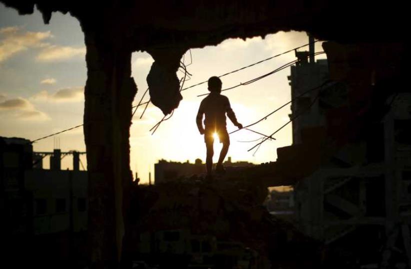 A Palestinian boy plays at a house that witnesses said was destroyed during Operation Protective Edge in the east of Gaza City (photo credit: REUTERS)