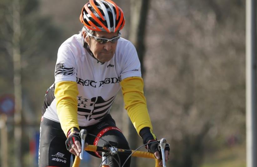United States Secretary of State John Kerry rides his bicycle along the shore of Lake Geneva (photo credit: REUTERS)