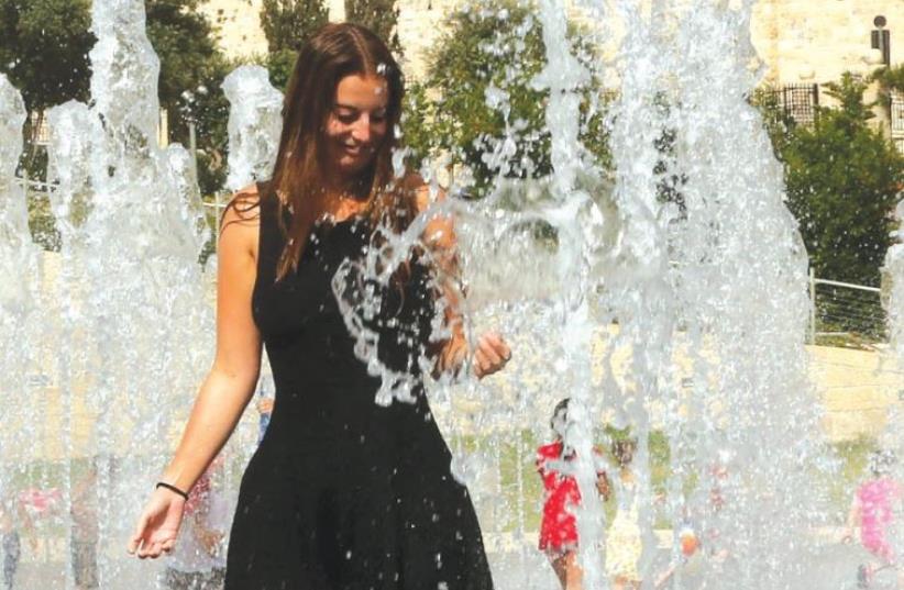 A woman plays in a water fountain in Jerusalem (photo credit: ILLUSTRATIVE: MARC ISRAEL SELLEM)