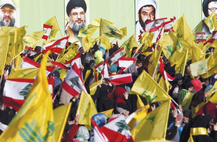 LOCALS IN NABATIYA, south Lebanon, carry Hezbollah and Lebanese flags on May 24 while the group’s leader Hassan Nasrallah speaks on a screen at a festival to commemorate the 15th anniversary of the IDF’s withdrawal from Lebanon (photo credit: REUTERS)
