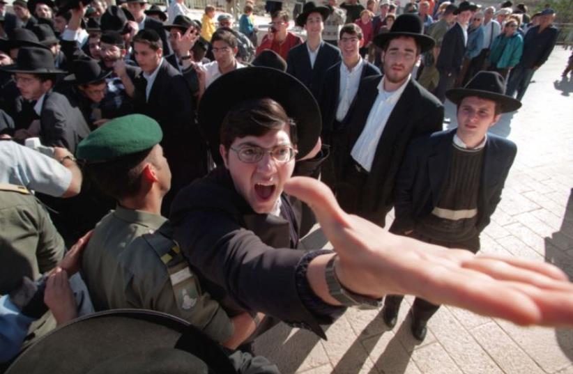 An ultra-orthodox Hassidic Jew is restrained by a Border Policeman as he screams against a group of Reform and Conservative rabbis holding prayers at the Western Wall (photo credit: REUTERS)