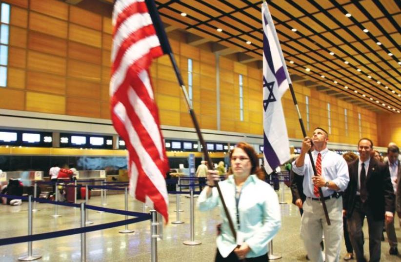 LOGAN INTERNATIONAL Airport staffers Tammy Carter and John Marietta parade the American and Israeli flags through the terminal on Sunday night to mark the launching of El Al’s Boston-Tel Aviv non-stop route (photo credit: TOVAH LAZAROFF)