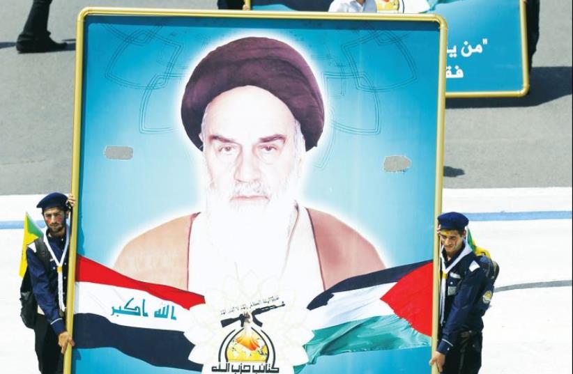 SHIITE MUSLIM men from Hashid Shaabi, a militia in Iraq, hold portraits of Iran’s late leader Ayatollah Ruhollah Khomeini during a parade in Baghdad (photo credit: REUTERS)