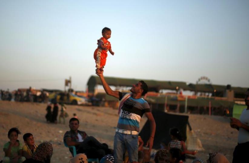 A Palestinian man lifts his daughter at beach along the Mediterranean Sea in the northern Gaza Strip July 24, 2015.  (photo credit: REUTERS)