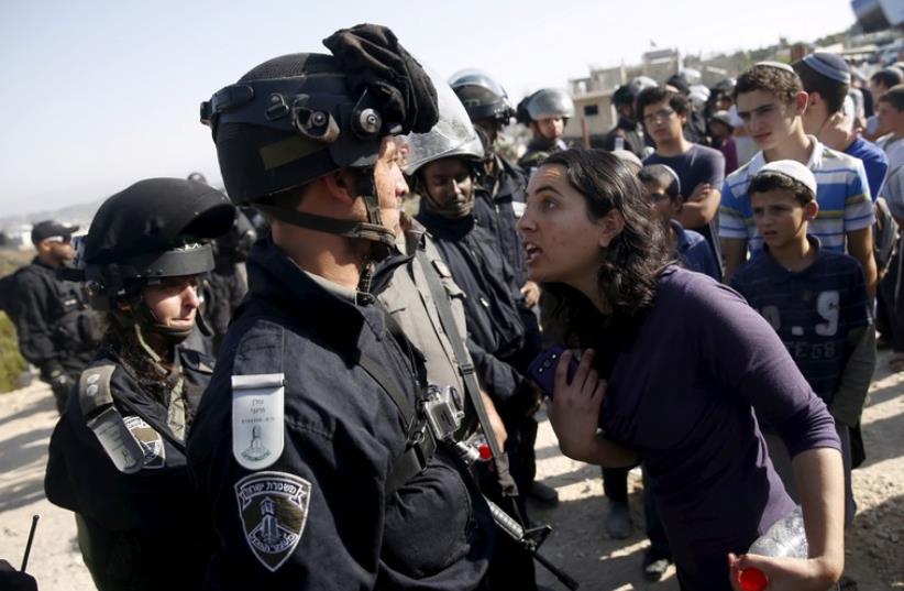 A young Jewish settler (R) speaks with an Israeli police officer near buildings slated for demolition in the West Bank Jewish settlement of Beit El (photo credit: REUTERS)