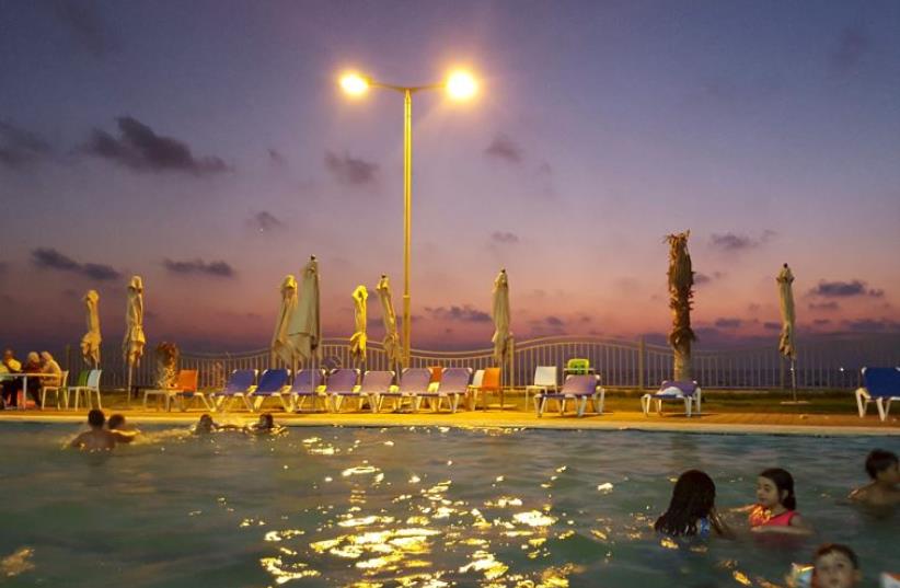 Palestinian children swim in a pool as they enjoy the warm weather with their families at the Blue Beach Resort in Gaza (photo credit: REUTERS)
