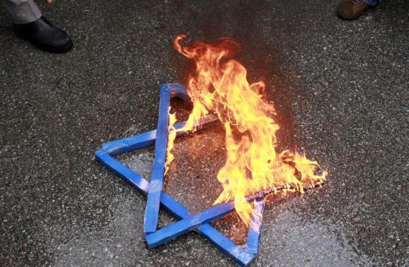 A Star of David burns in flames during a protest against Israeli attacks on Gaza in front of the Israeli embassy in Ankara (photo credit: REUTERS)