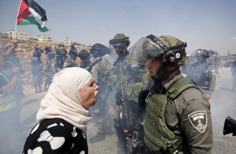 A Palestinian woman argues with an Israeli border policeman during a protest against Jewish settlements in the West Bank village of Nabi Saleh (photo credit: REUTERS)