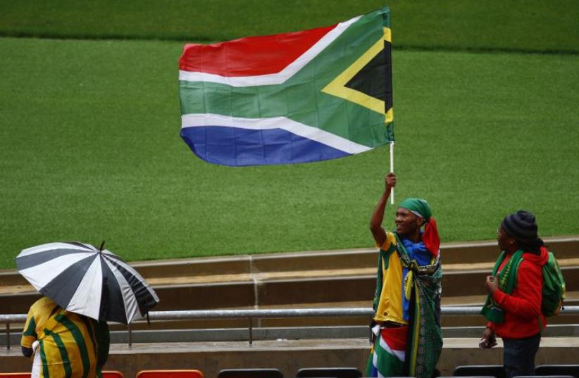 A man raises the South African national flag during the service for former South African President Nelson Mandela at the First National Bank Stadium (photo credit: REUTERS)