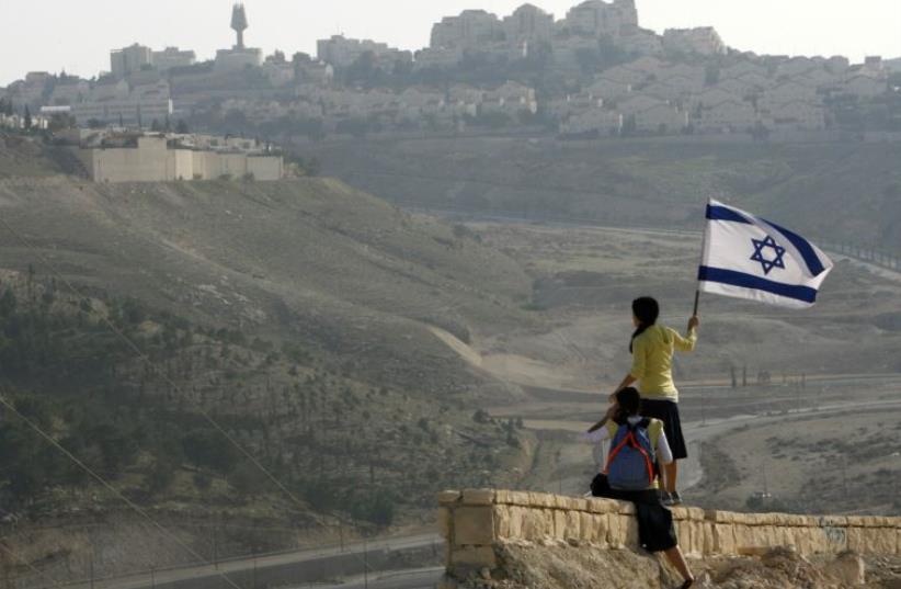 A girl holds an Israeli flag on a hilltop near the Maaleh Adumim settlement (photo credit: REUTERS)