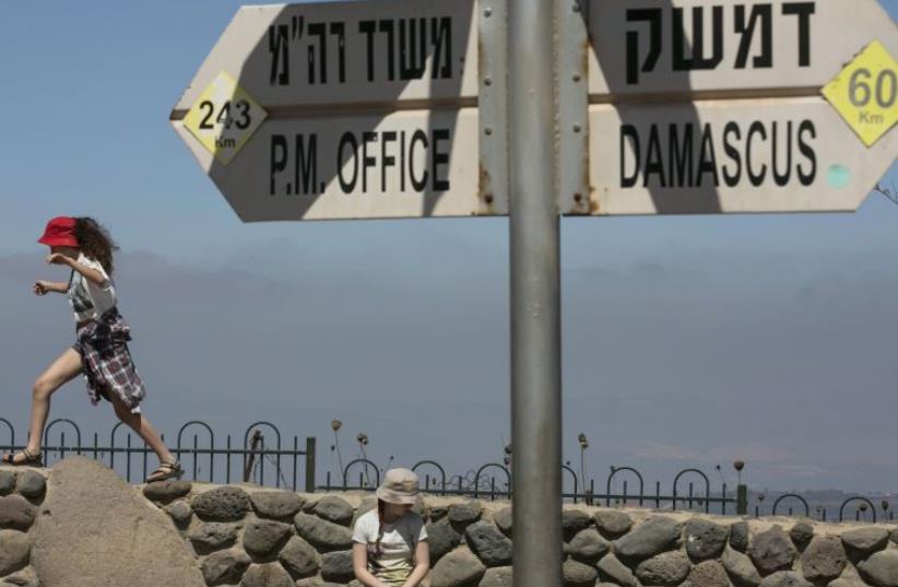 Girls play near a sign at Mount Bental, an observation post on the Israeli side of the Golan Heights, overlooking the Syrian side of the Kuneitra crossing (photo credit: REUTERS/BAZ RATNER)